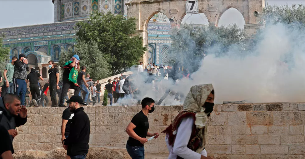 متظاهرون فلسطينيون يهربون من قنابل الغاز المسيل للدموع الذي أطلقته القوات الإسرائيلية خلال الاشتباكات الدائرة في باحات المسجد الأقصى في القدس الشرقية