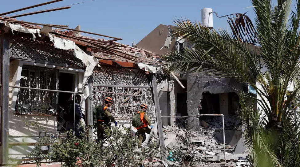 خبراء ألغام إسرائيليون يسيرون في منزل مدمر في مدينة عسقلان جنوب إسرائيل في 11 مايو 2021