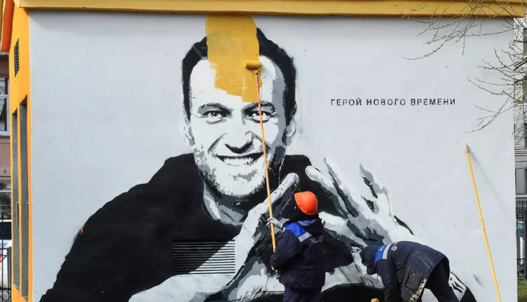 عامل يغطي رسم غرافيتي لصورة المعارض السياسي الروسي المسجون أليكسي نافالني في سان بطرسبوغ