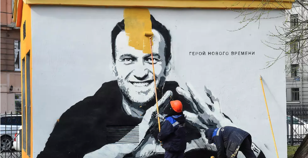 عامل يغطي رسم غرافيتي لصورة المعارض السياسي الروسي المسجون أليكسي نافالني في سان بطرسبوغ
