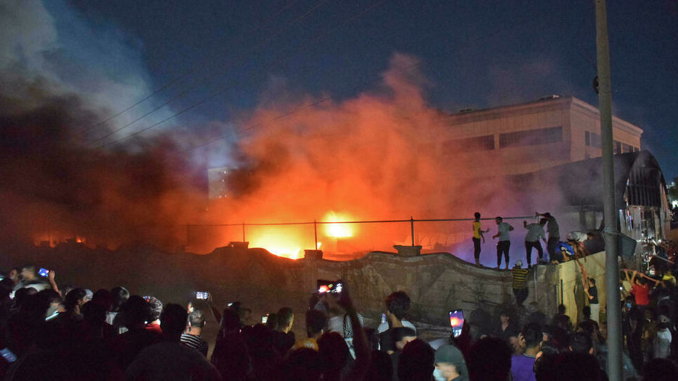 أشخاص يلتقطون صورا لحريق هائل شب في منشأة لعزل مرضى كوفيد-19 في مستشفى الحسين في الناصرية بجنوب العرق